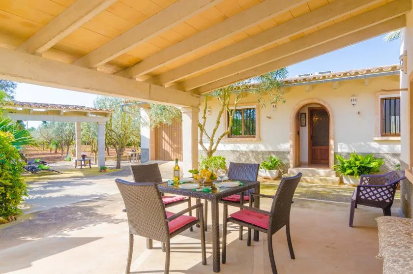 Un patio cubierto con una mesa de comedor y asientos junto a una casa.
