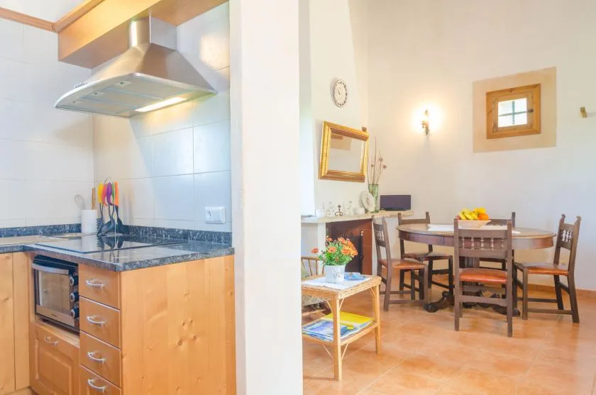 Una cocina se abre a un comedor con una mesa de madera y sillas.