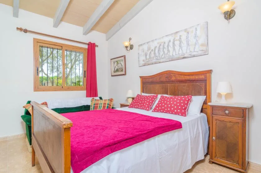 Un dormitorio con una cama de madera vestida con ropa de cama blanca y rosa intenso.