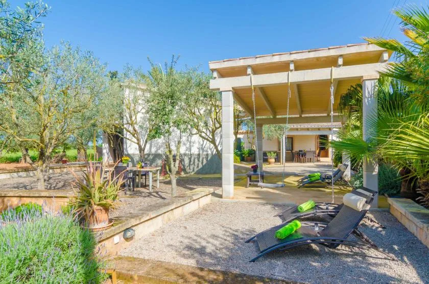 Un patio al aire libre con asientos reclinables bajo una pérgola cubierta.