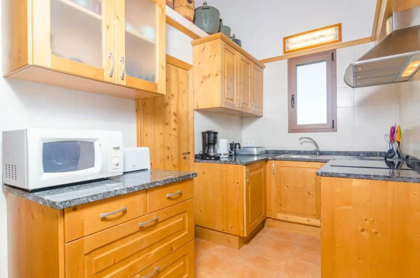 Una cocina luminosa con armarios de madera, encimeras y una ventana sobre el fregadero.