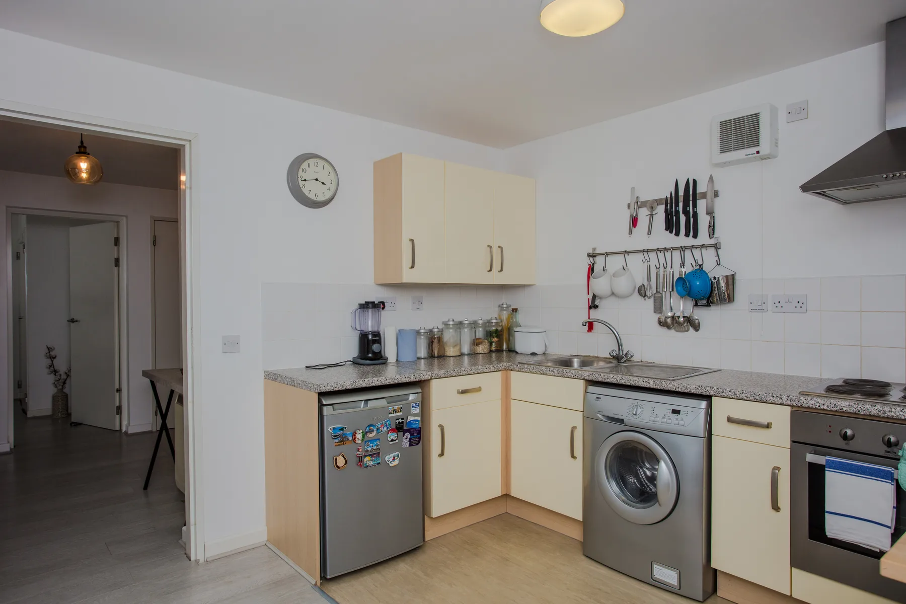 A compact kitchen with light cabinets, a countertop, and a washing machine.