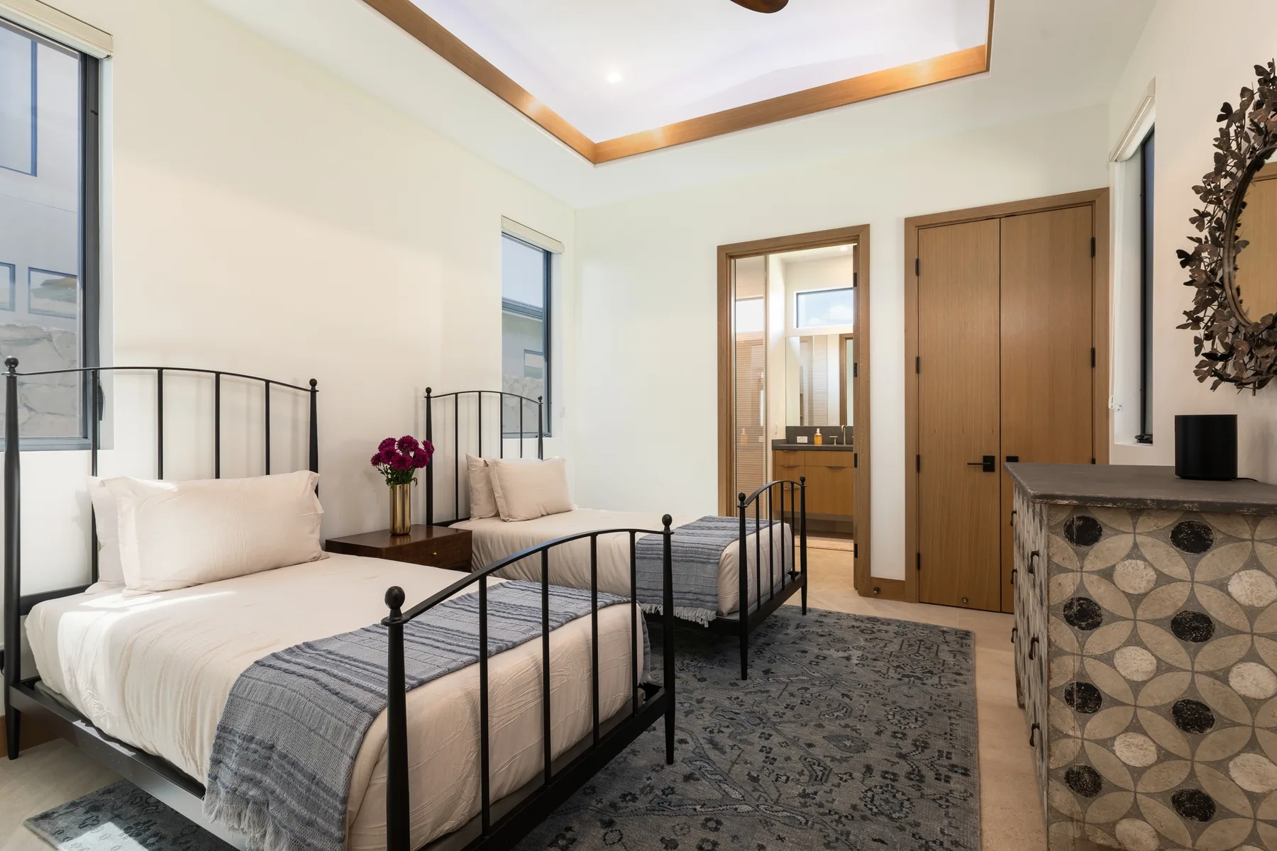 A bedroom with two single beds, a patterned rug, and a wooden door.