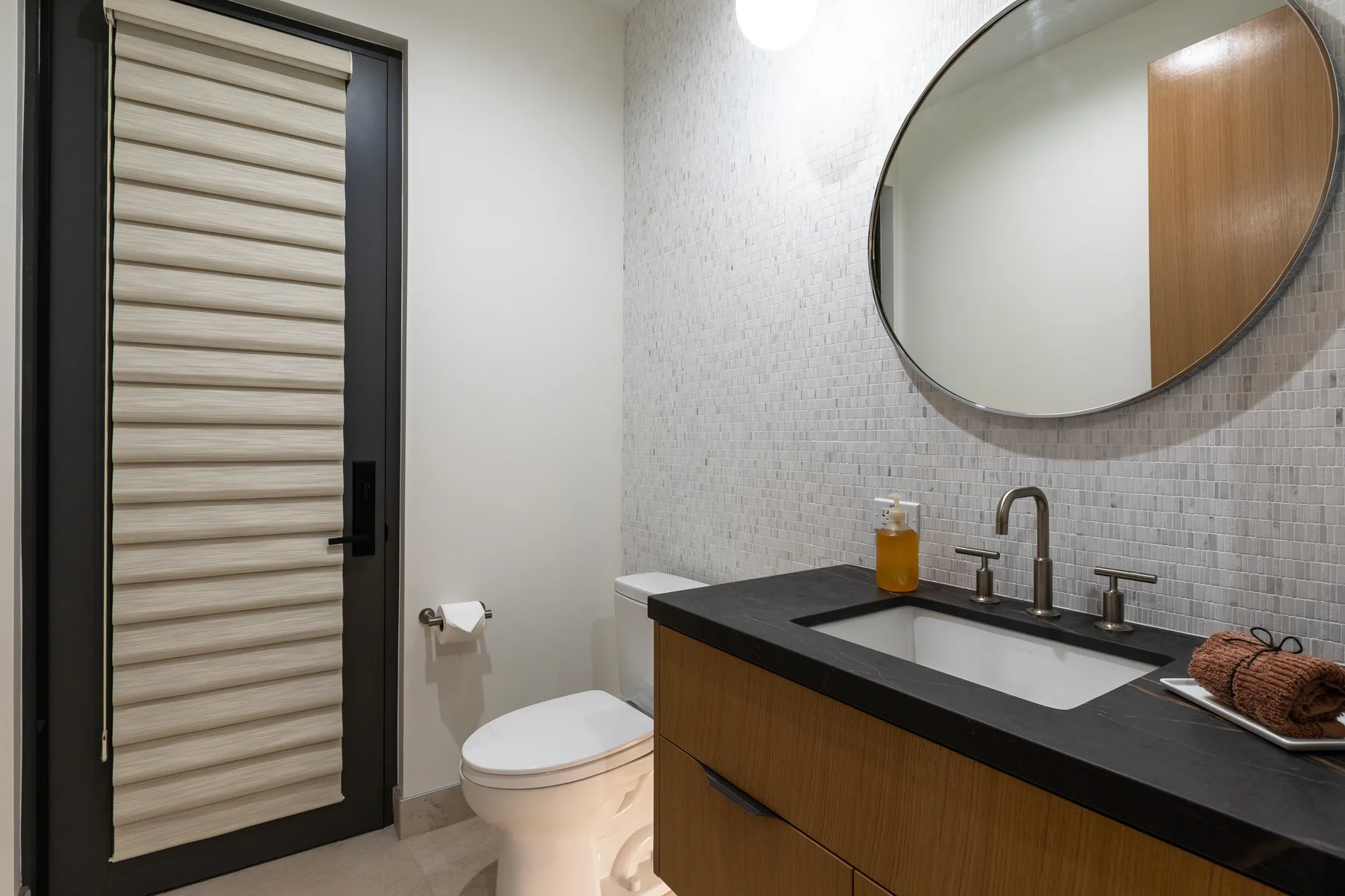 A modern bathroom with a vanity, sink, and large round mirror.