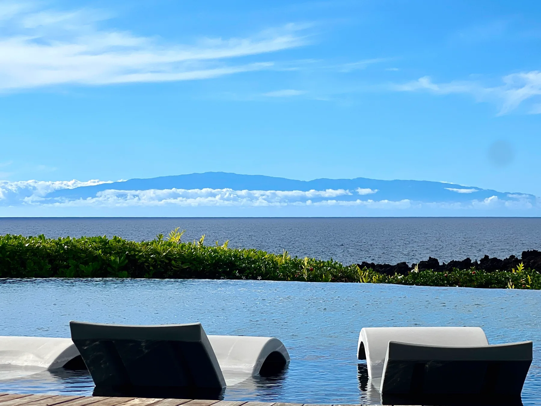 An infinity pool overlooks the sea and a distant mountain range.