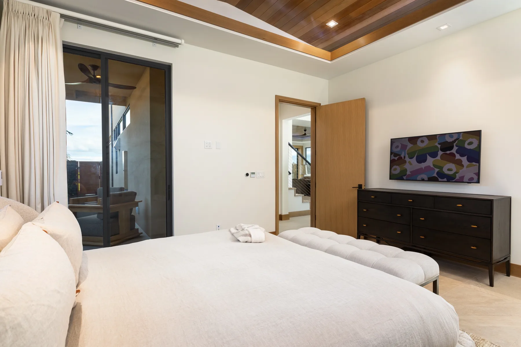 A bedroom with a large bed, dark dresser, and television.