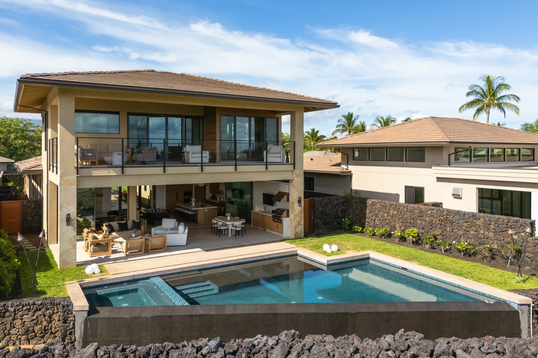 A modern house overlooks a swimming pool and landscaped yard.