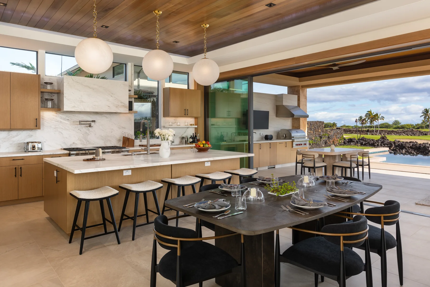 Una cocina abierta con comedor cuenta con una isla y una mesa junto a amplios ventanales.