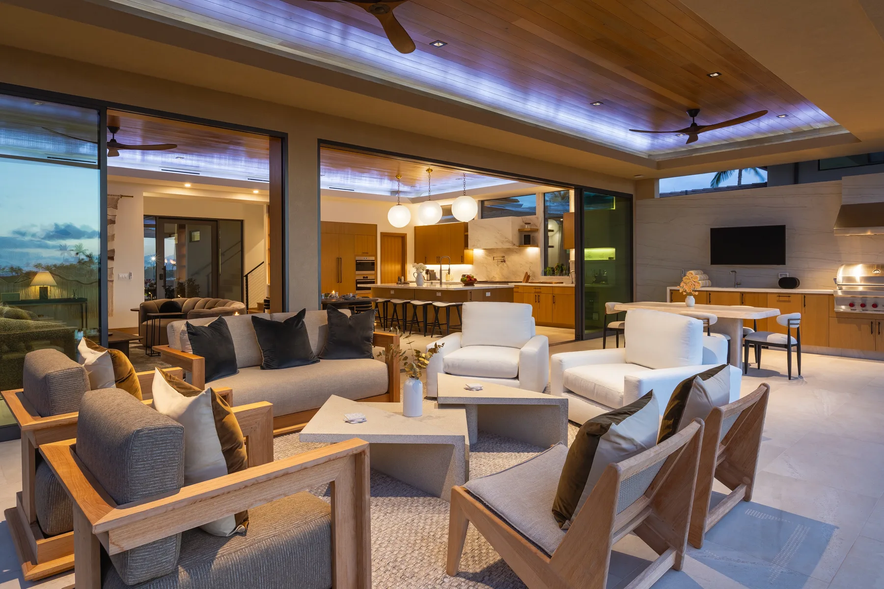 A spacious living room opens onto a kitchen, with seating arranged around a low table.