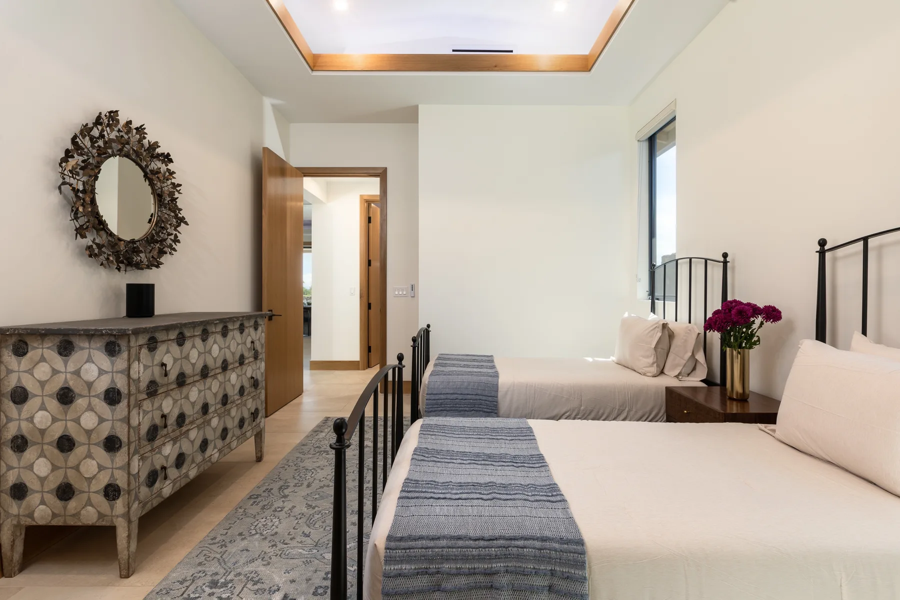 A bedroom with two beds, patterned textiles, and a decorative dresser.