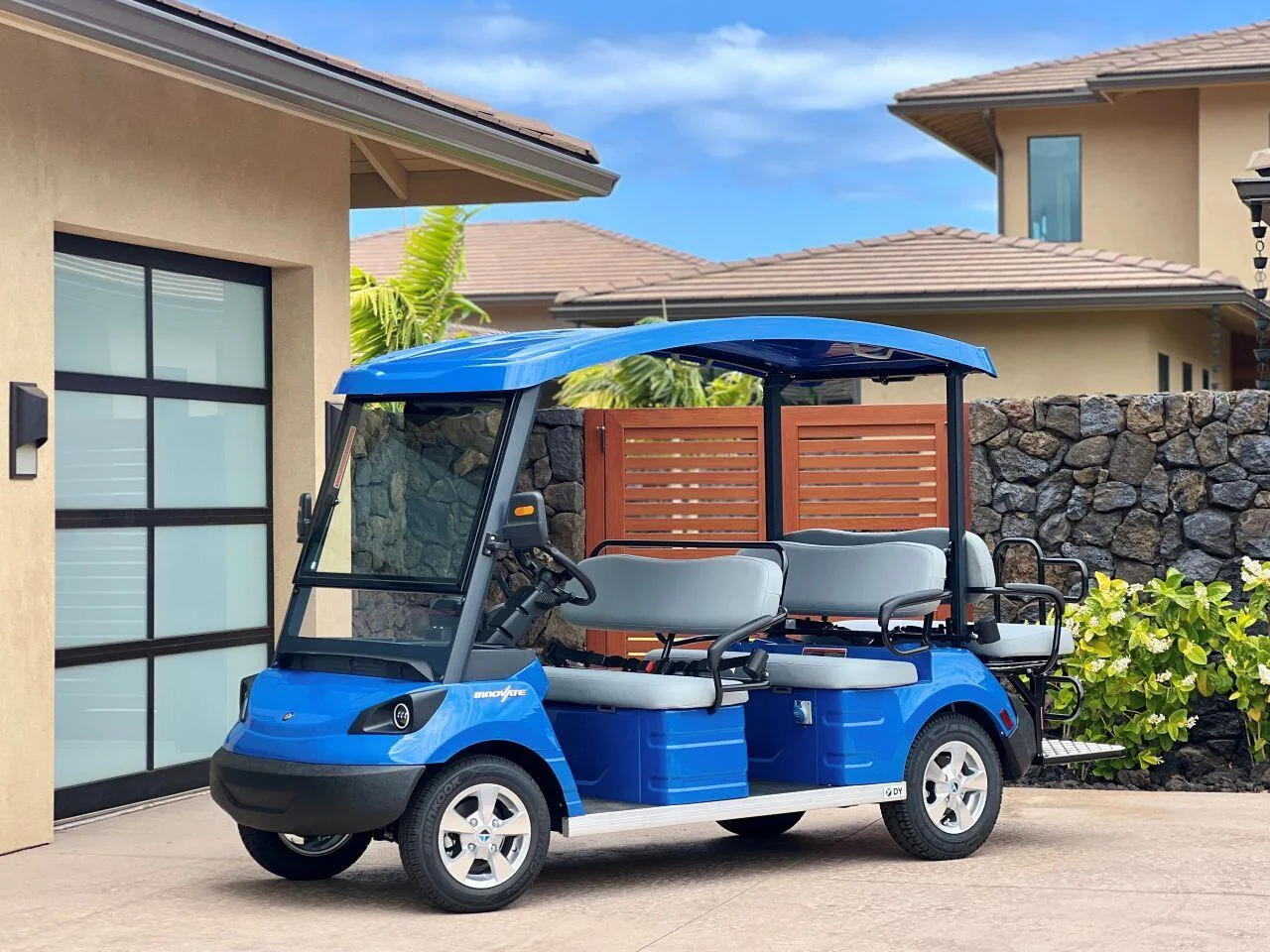 A blue golf cart is parked in a paved outdoor courtyard.