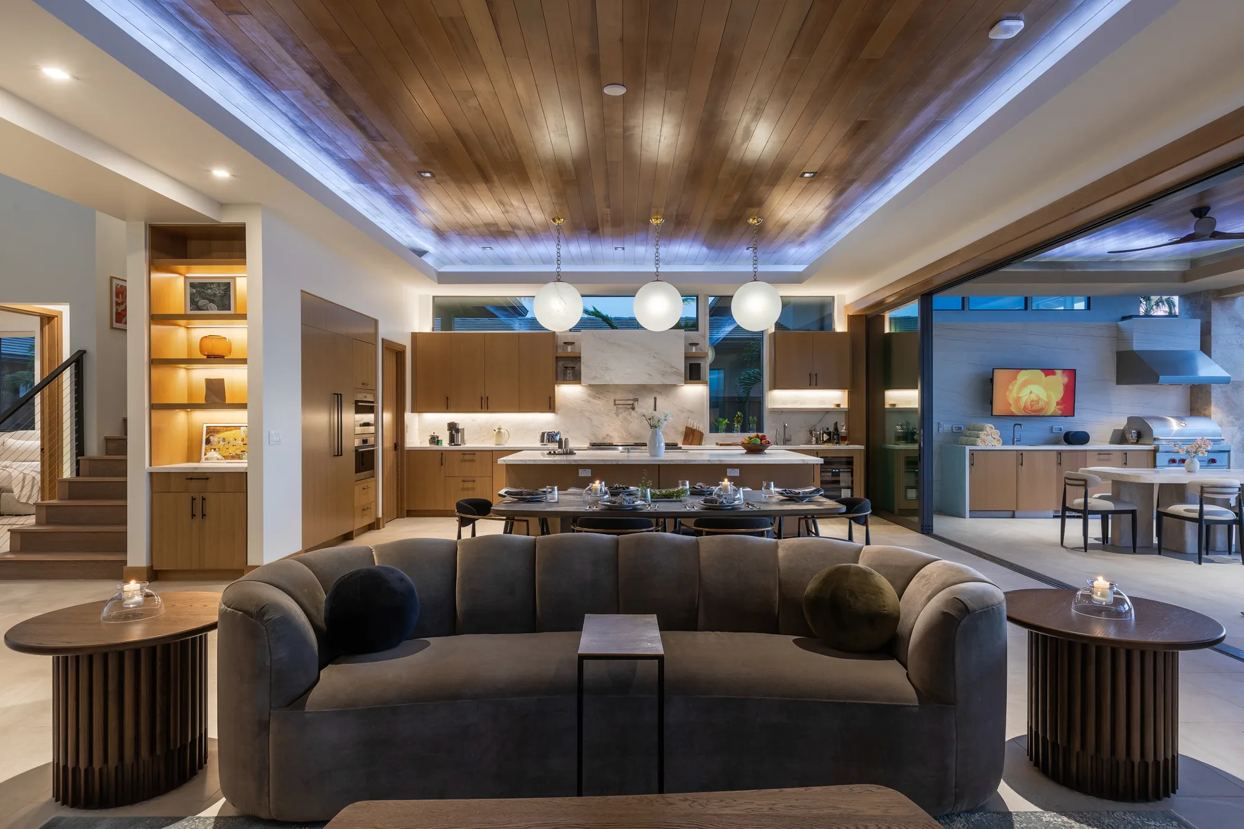 A spacious living area opens onto a kitchen and dining space, with a curved sofa in front.