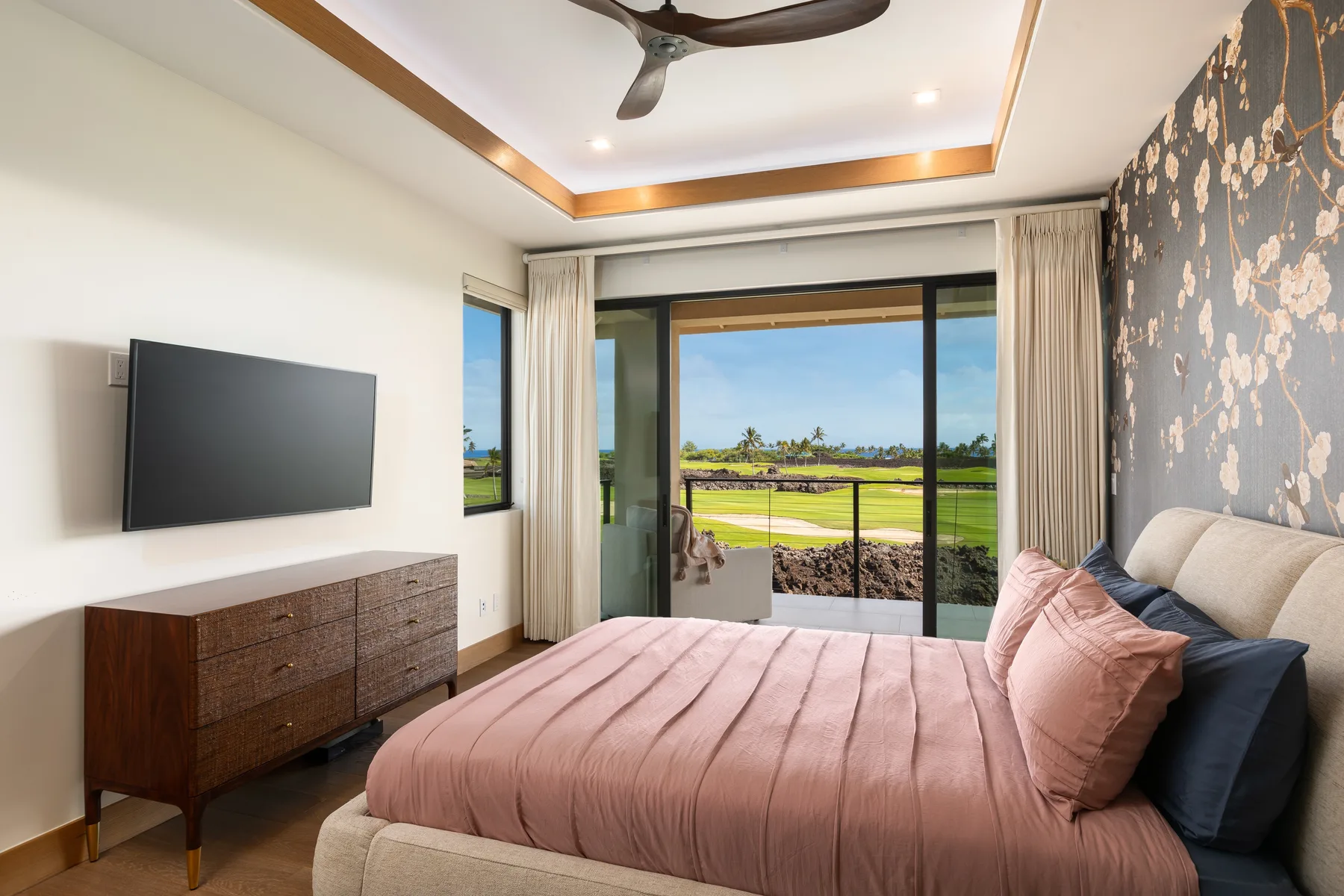 A bedroom with a bed facing sliding glass doors and an open landscape view.