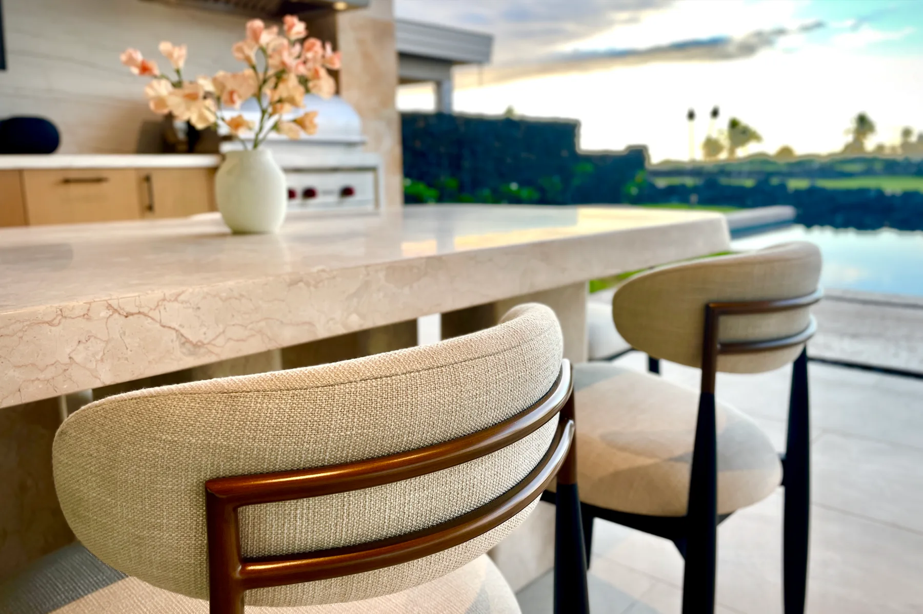 A kitchen island with upholstered seating and a vase of flowers.