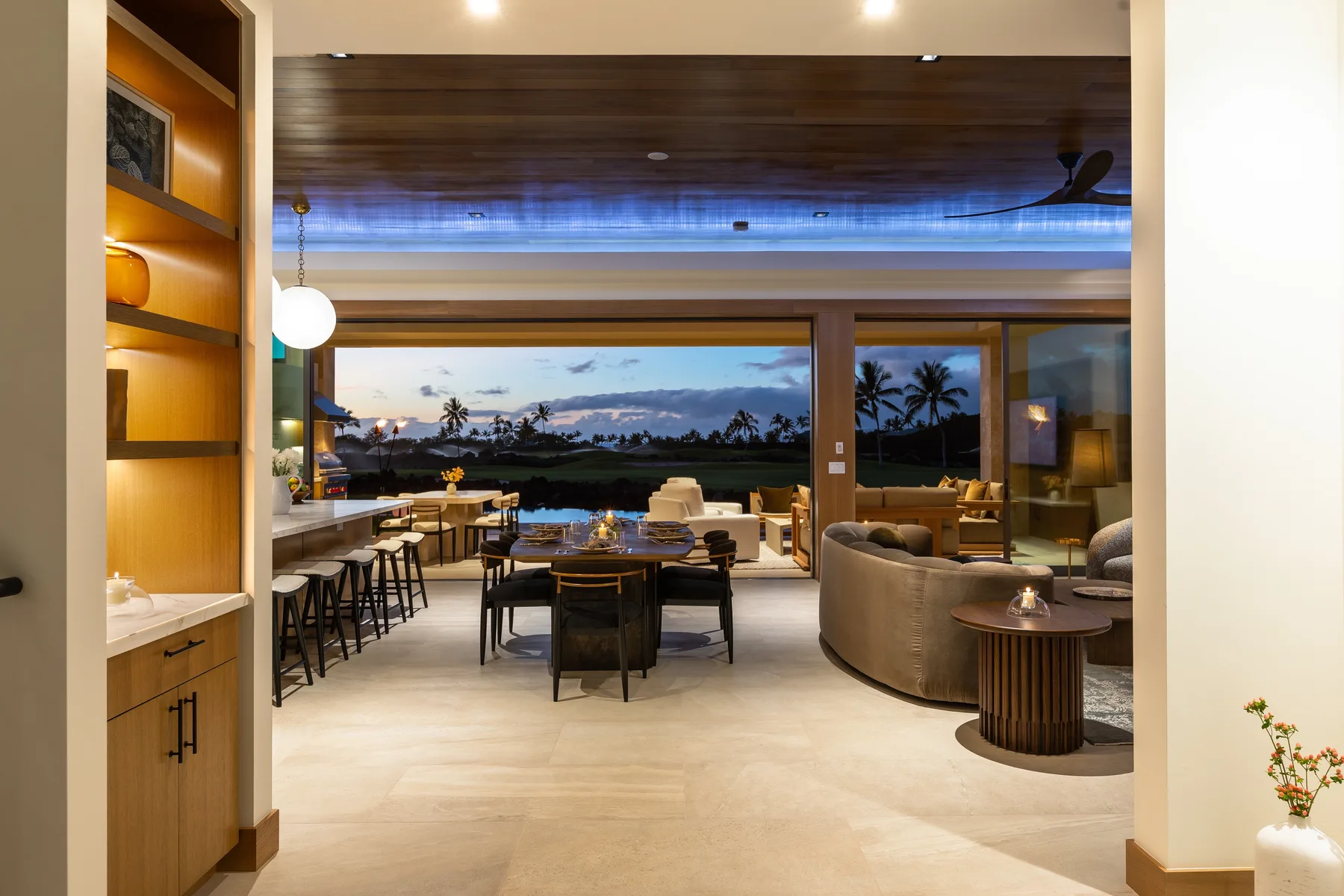 An open-plan dining and living area faces large windows overlooking a coastal landscape.