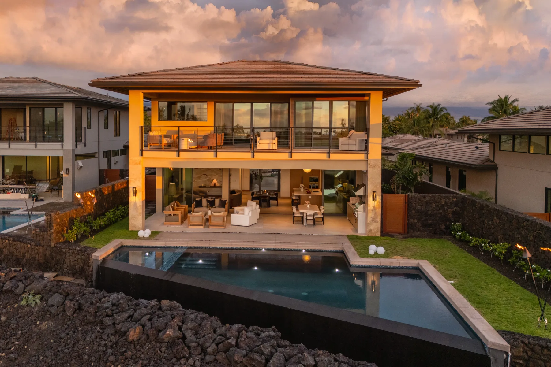 A modern two-story house overlooks a swimming pool and landscaped garden.