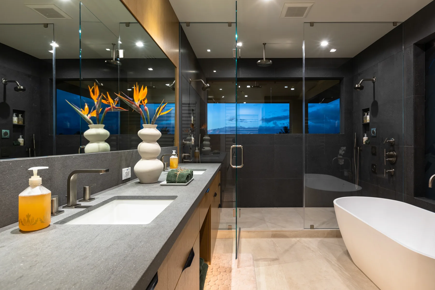 A modern bathroom with a wide vanity, glass shower, and freestanding bathtub.