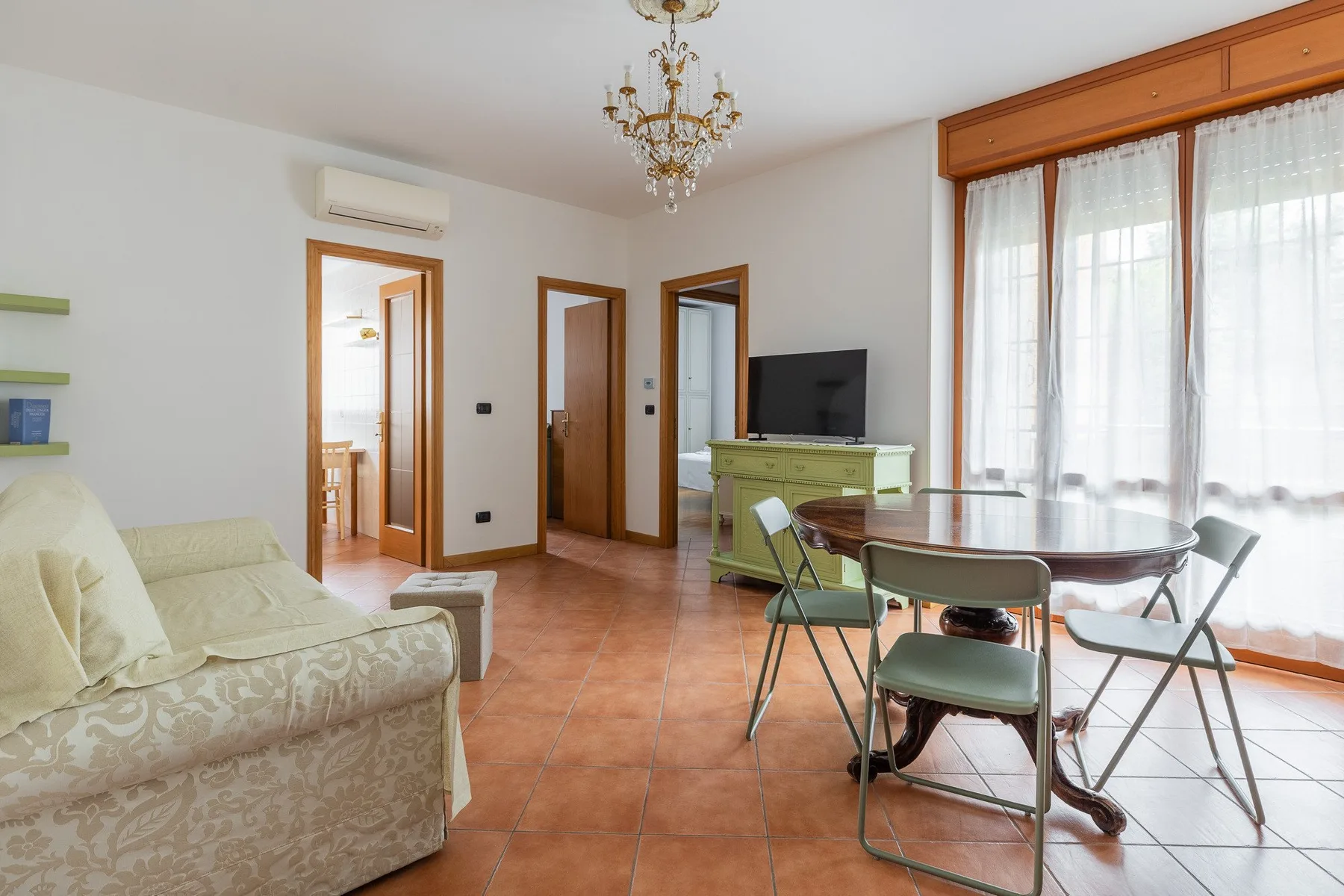 A bright living and dining room with seating beside large windows.