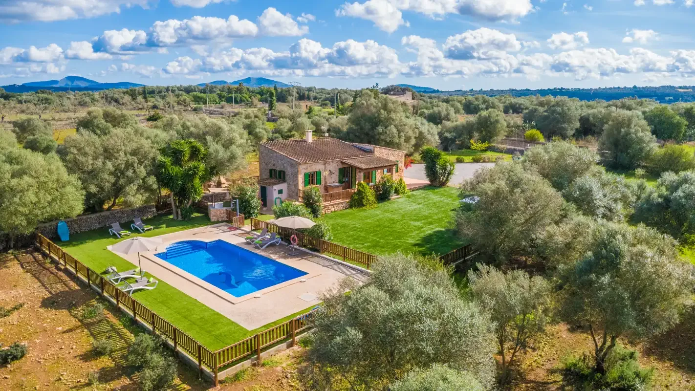 A countryside house stands beside a blue swimming pool and green lawn.