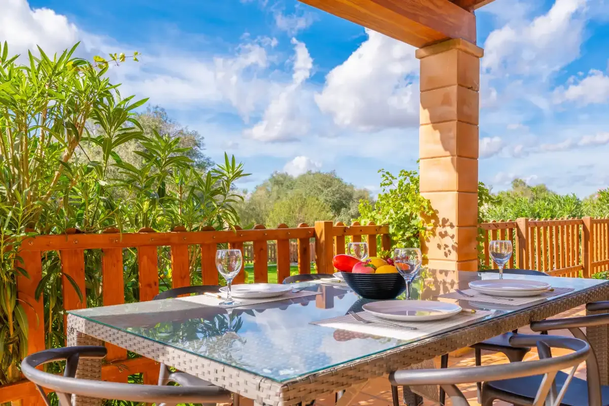 An outdoor dining area with a glass-topped table and wooden railing.