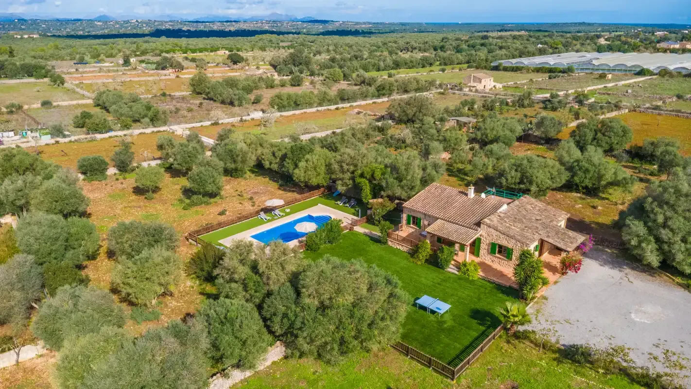 An aerial view of a countryside house beside a garden and swimming pool.