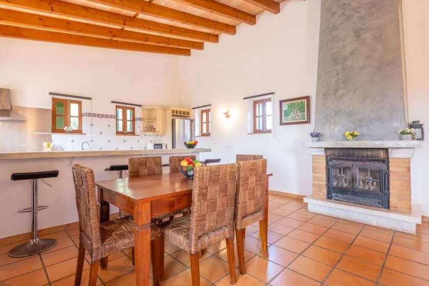 A dining area with a wooden table beside a kitchen counter and fireplace.