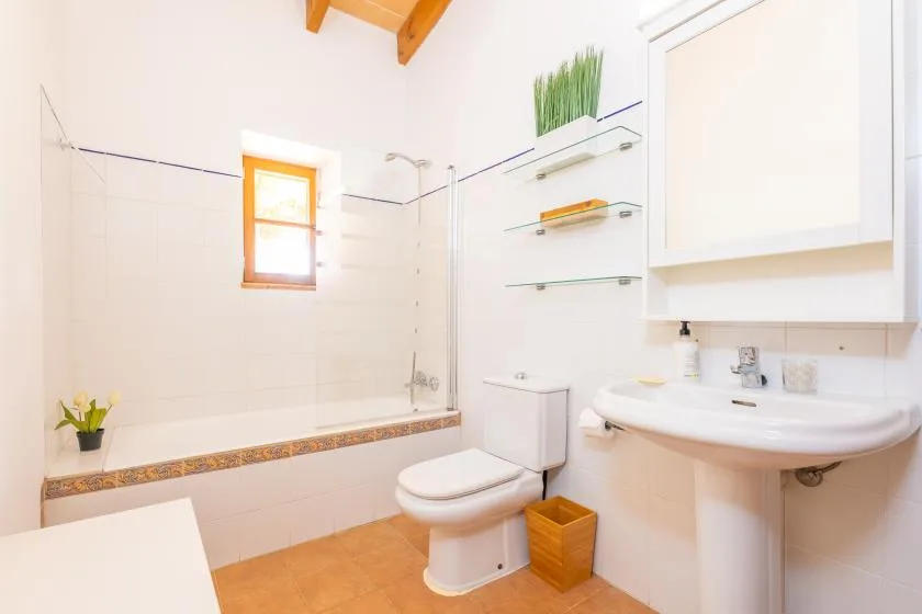 A bright bathroom with a bathtub, toilet, and pedestal sink.