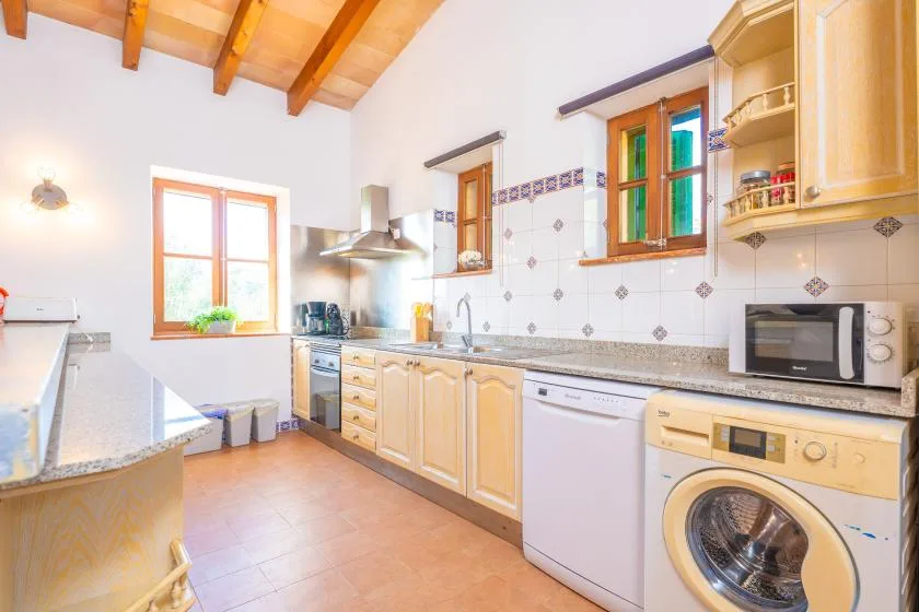 A bright kitchen with light wood cabinets, a tiled backsplash, and a washing machine.