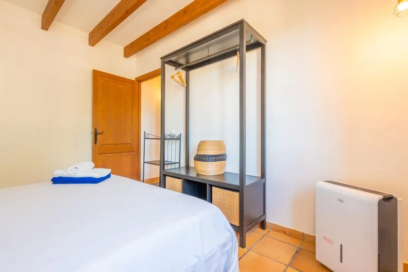 A bedroom with a bed and an open clothing rack.