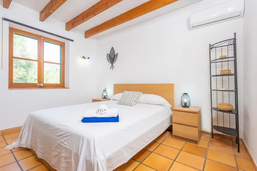A bedroom with a double bed, wooden beams, and a window.
