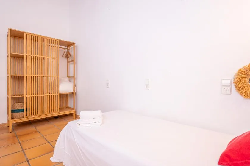A bedroom with a bed beside a wooden shelving unit.