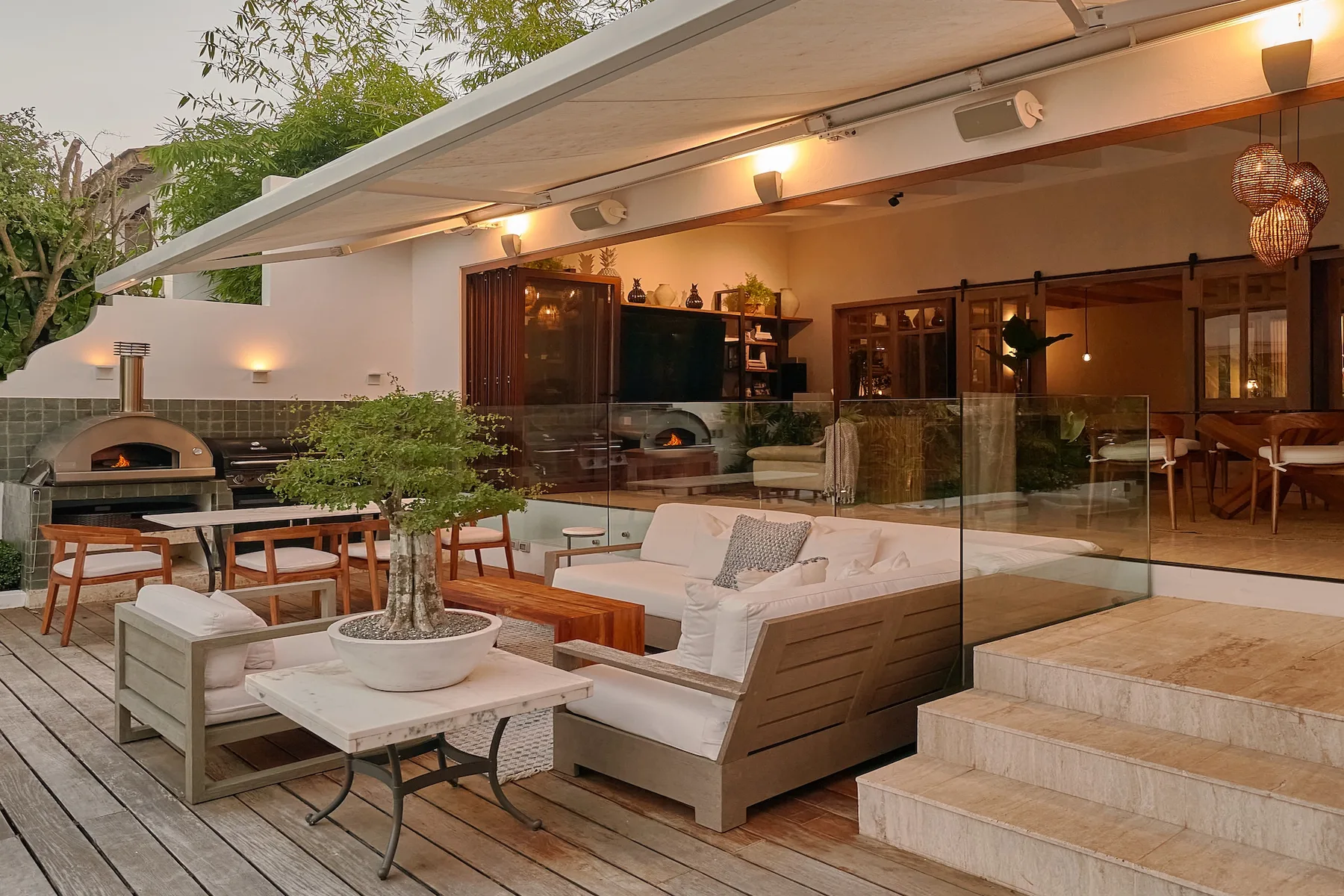 An outdoor lounge and dining area with cushioned seating beside a glass railing.
