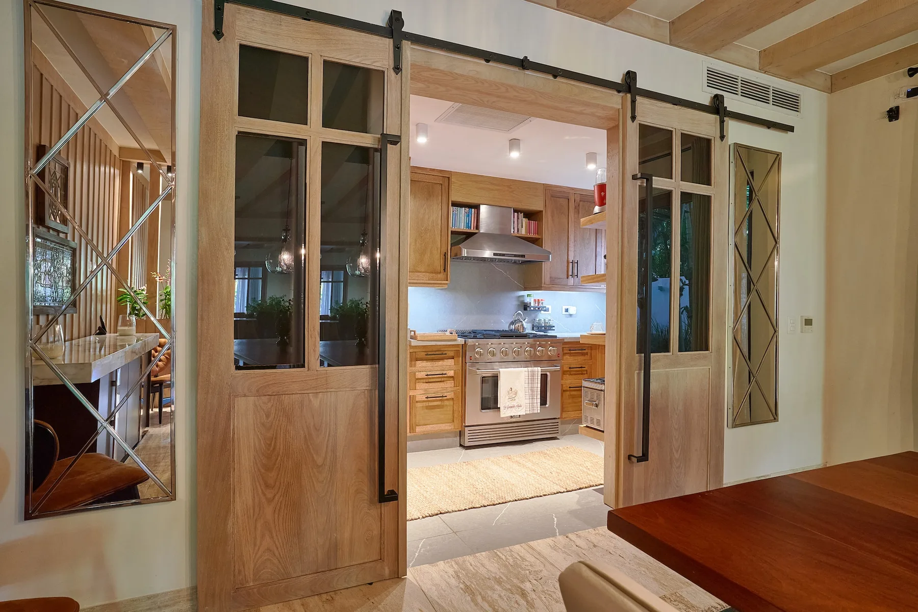 A kitchen is visible through open wooden sliding doors, with cabinets and a stove.