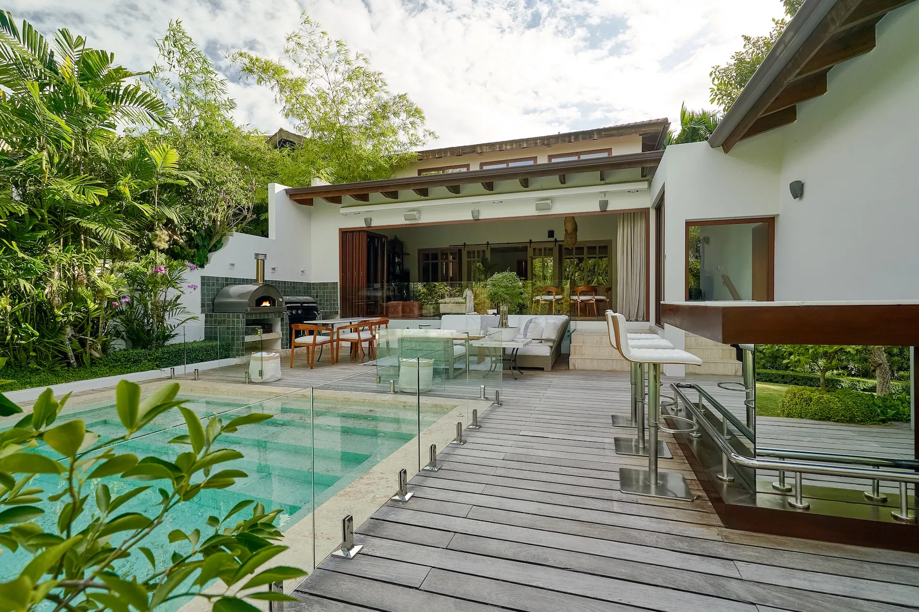 An outdoor poolside patio with dining and seating beside the house.