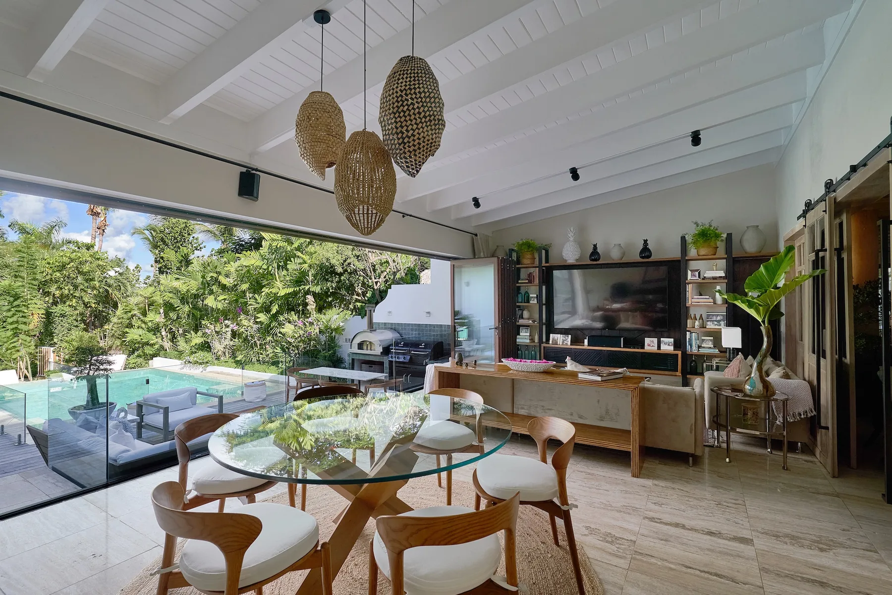 Una luminosa sala de estar y comedor diáfana se abre a un jardín y una piscina.