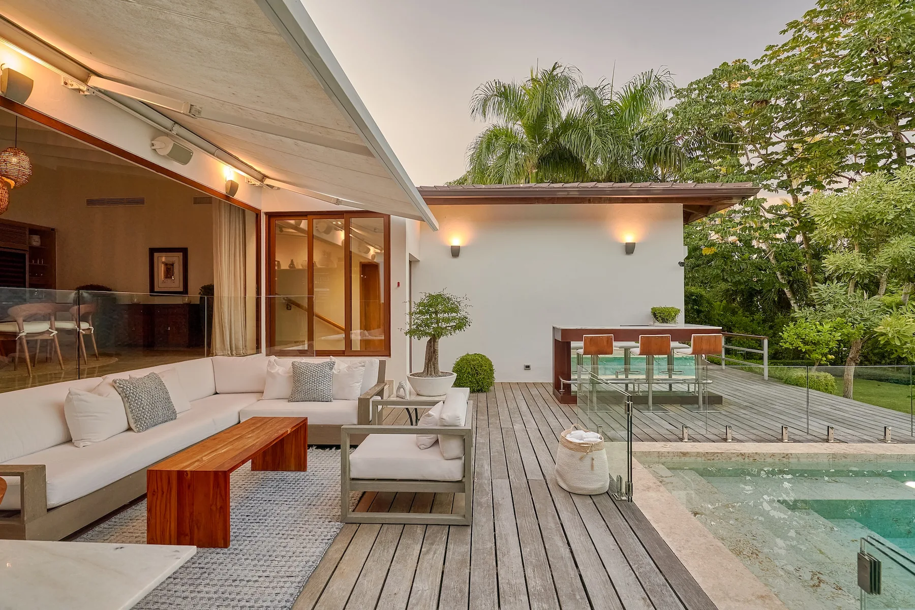An outdoor patio with lounge seating, a dining table, and a pool beside it.
