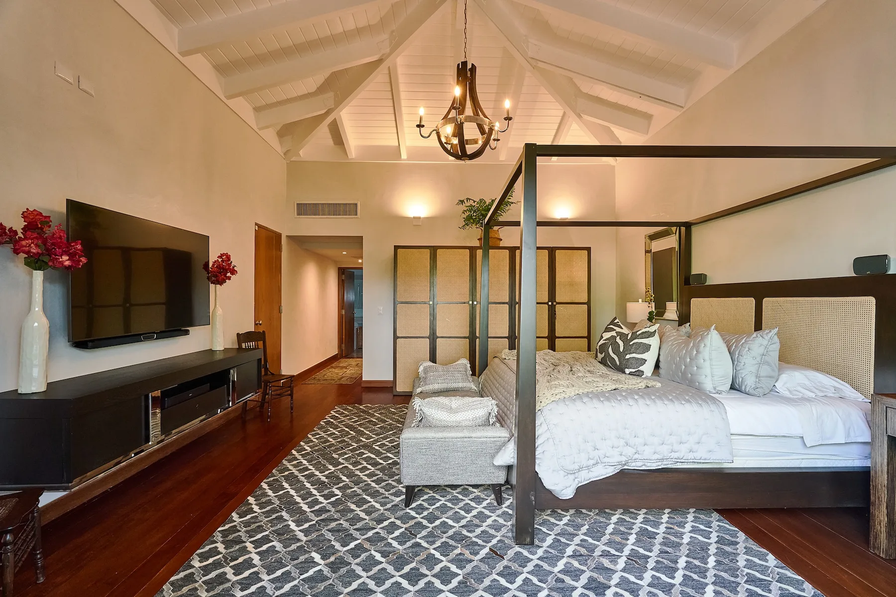 A spacious bedroom features a four-poster bed and a patterned rug.