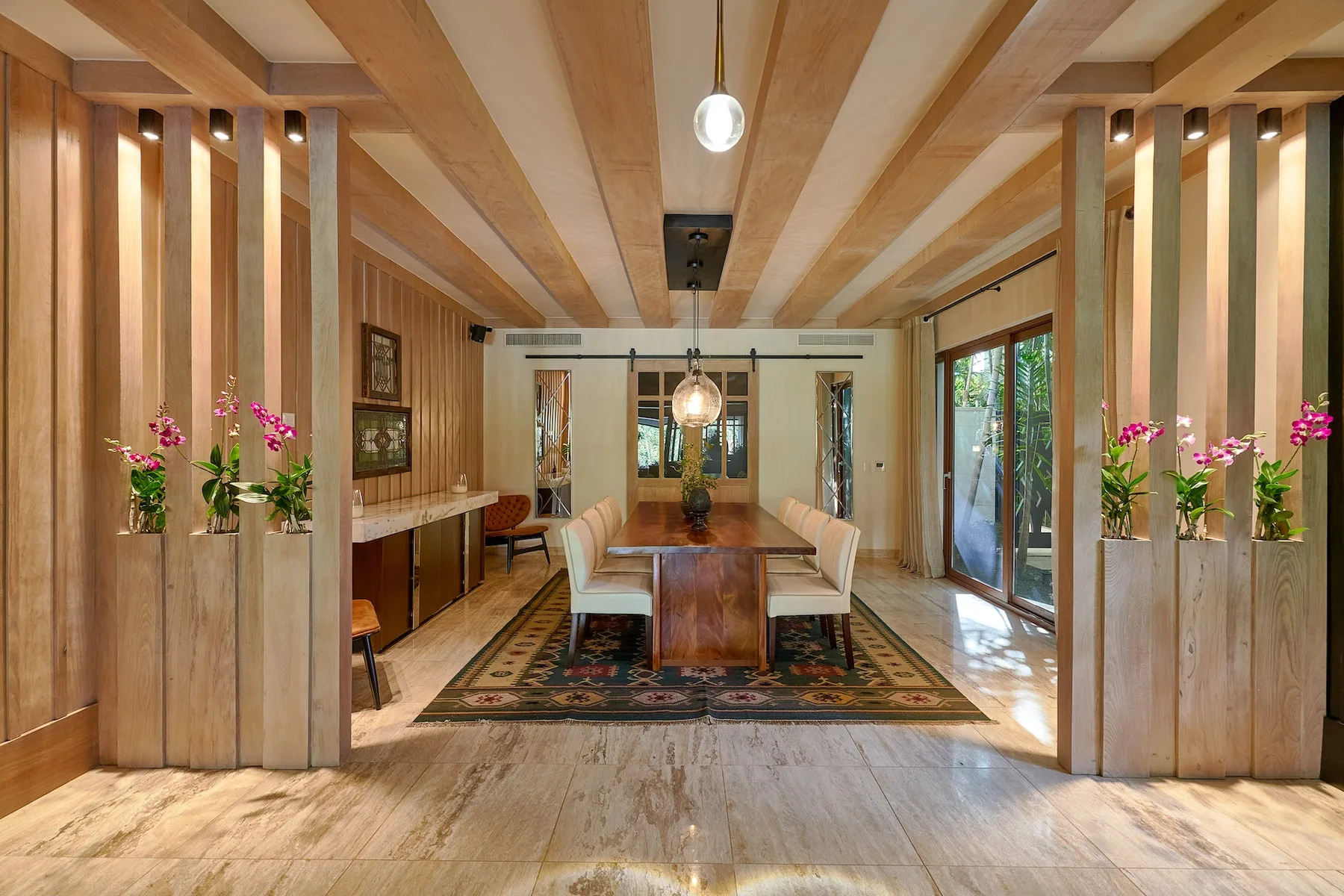 A dining area with a long wooden table, seating, and exposed ceiling beams.