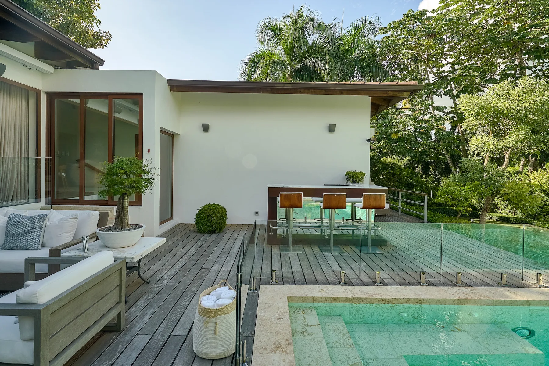 A modern outdoor patio with seating, a dining table, and a swimming pool.