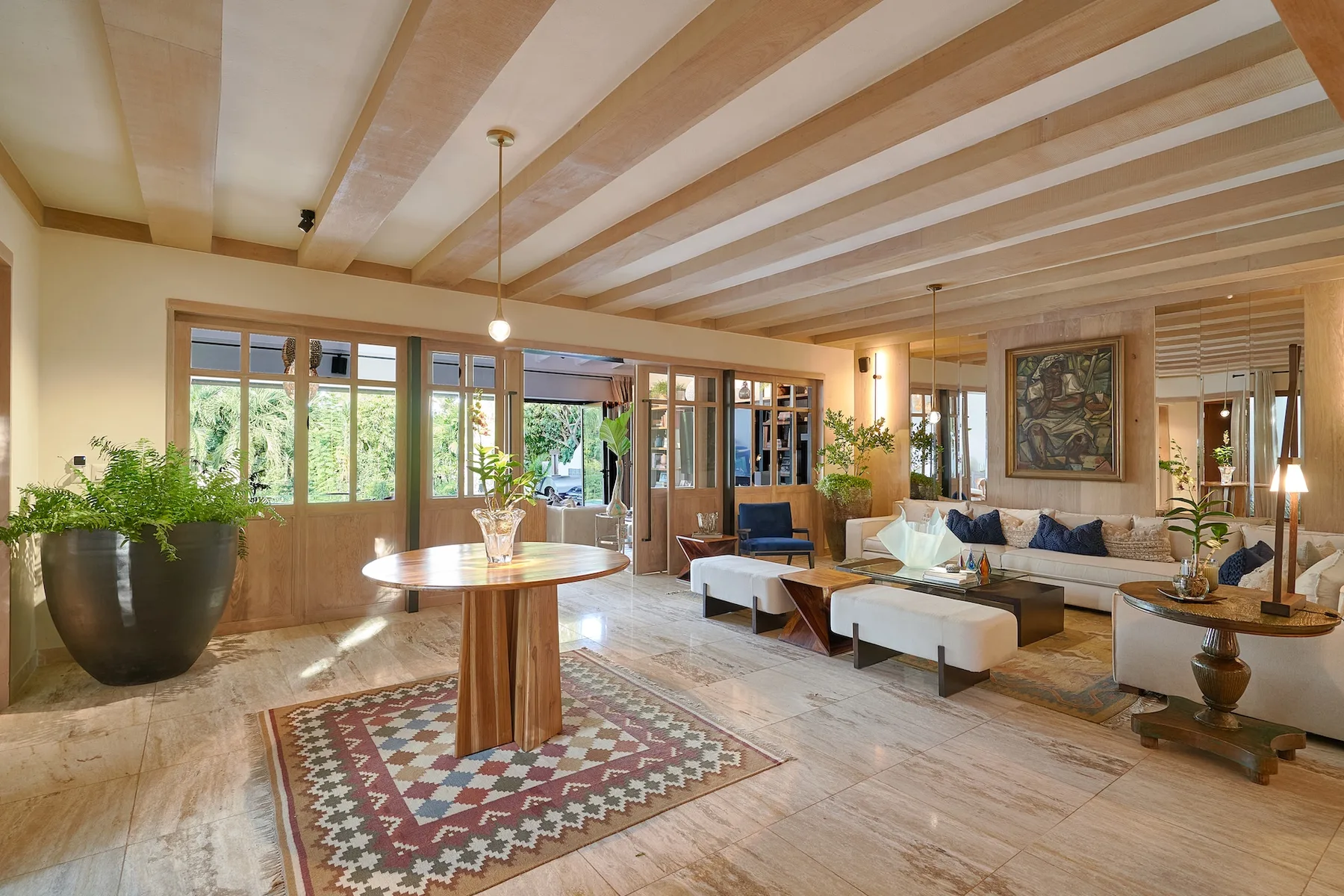 A spacious living room with seating, large windows, and exposed ceiling beams.