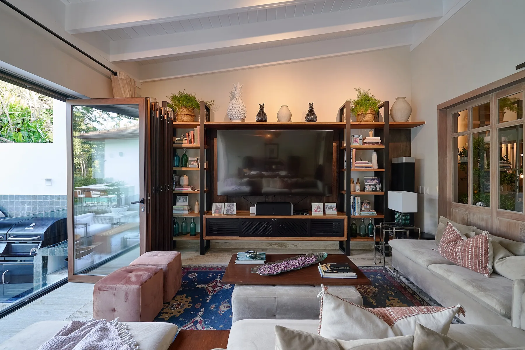 A living room with a television, shelving, and seating around a patterned rug.