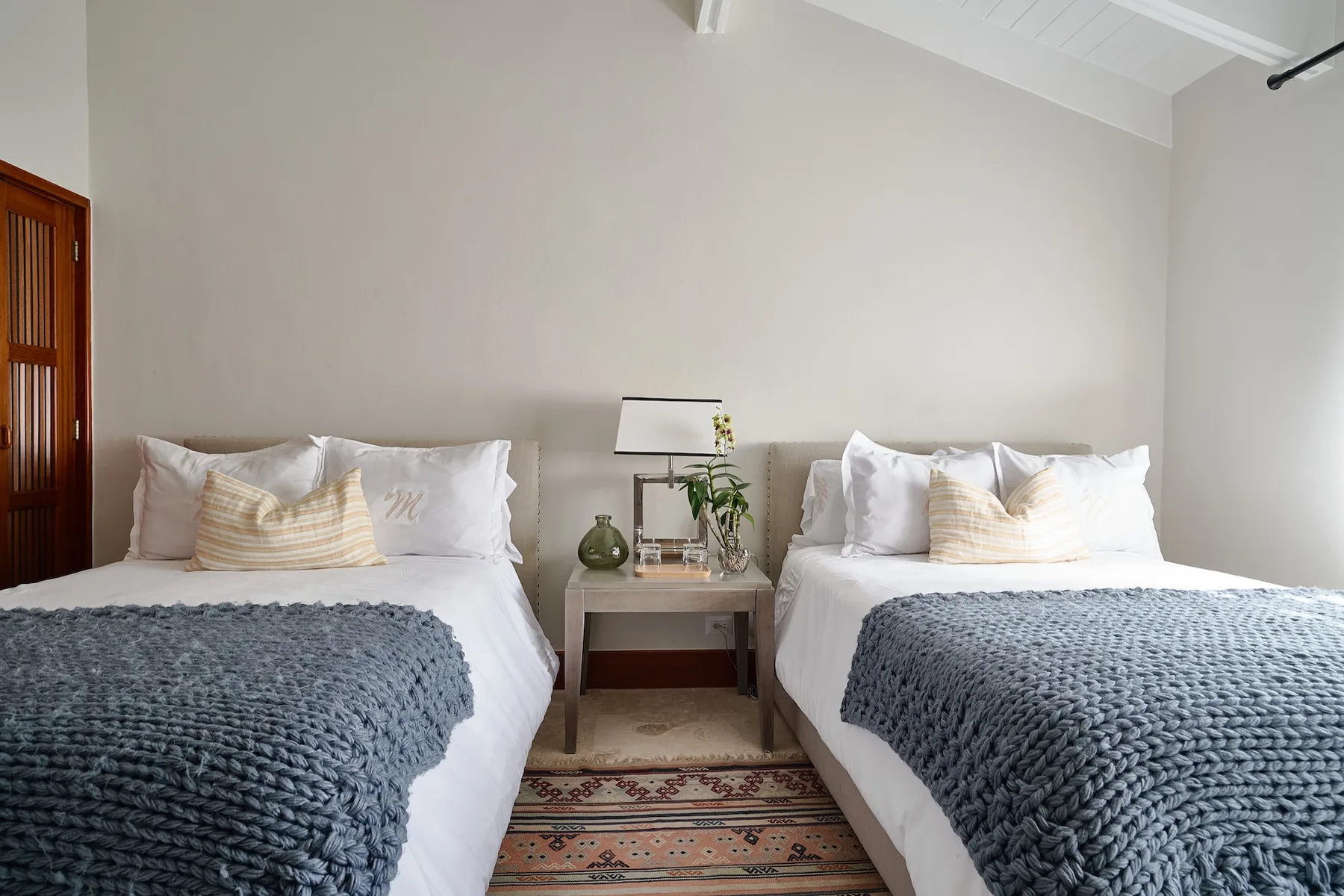 A bedroom with two beds and a small table between them.