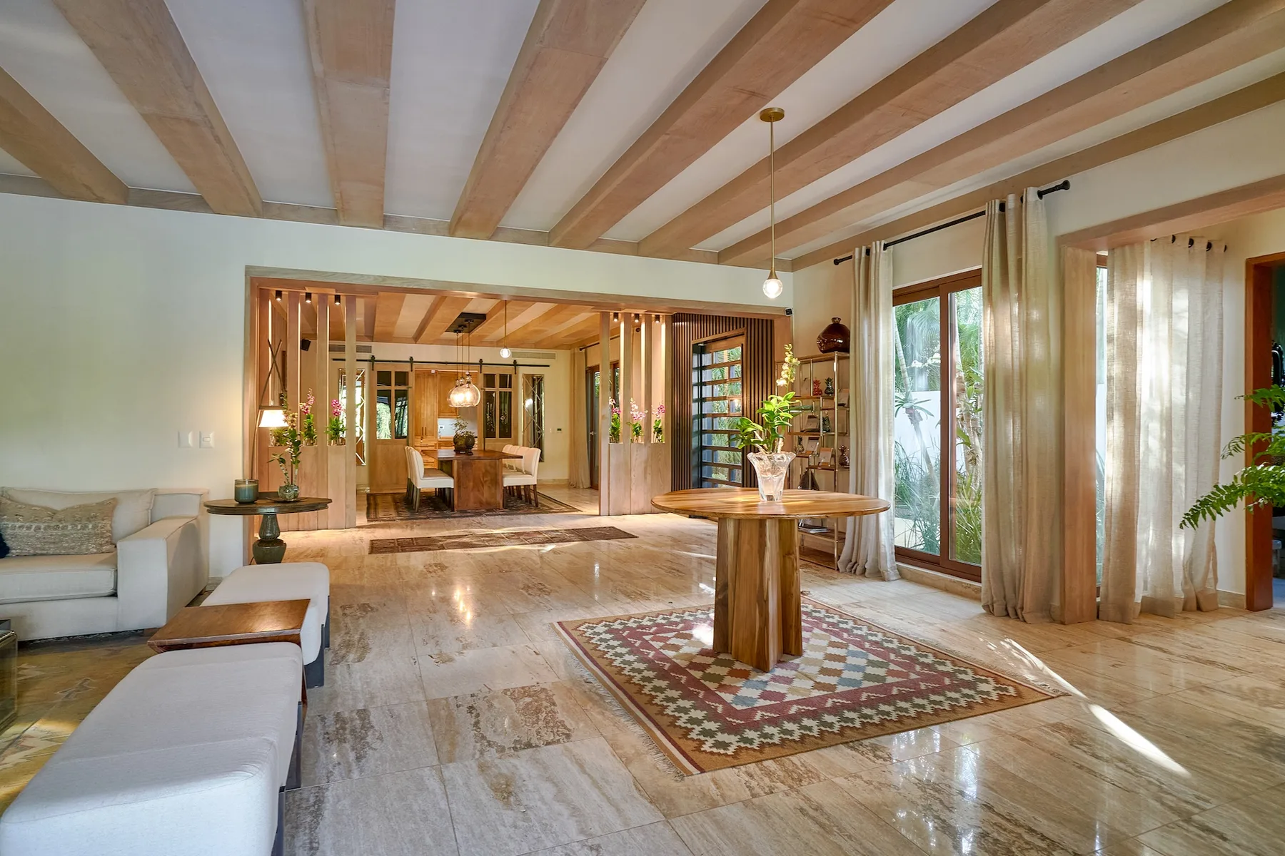 A spacious living room with exposed ceiling beams and a large wooden table.