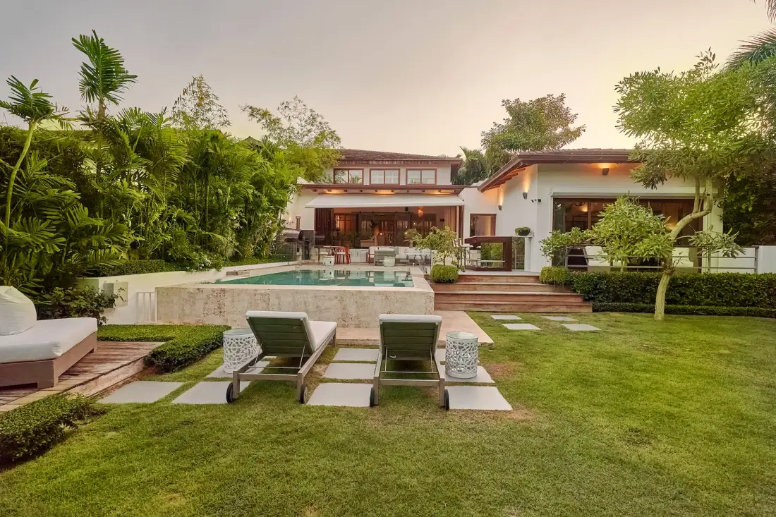 A landscaped outdoor pool area with loungers, a lawn, and a modern building.