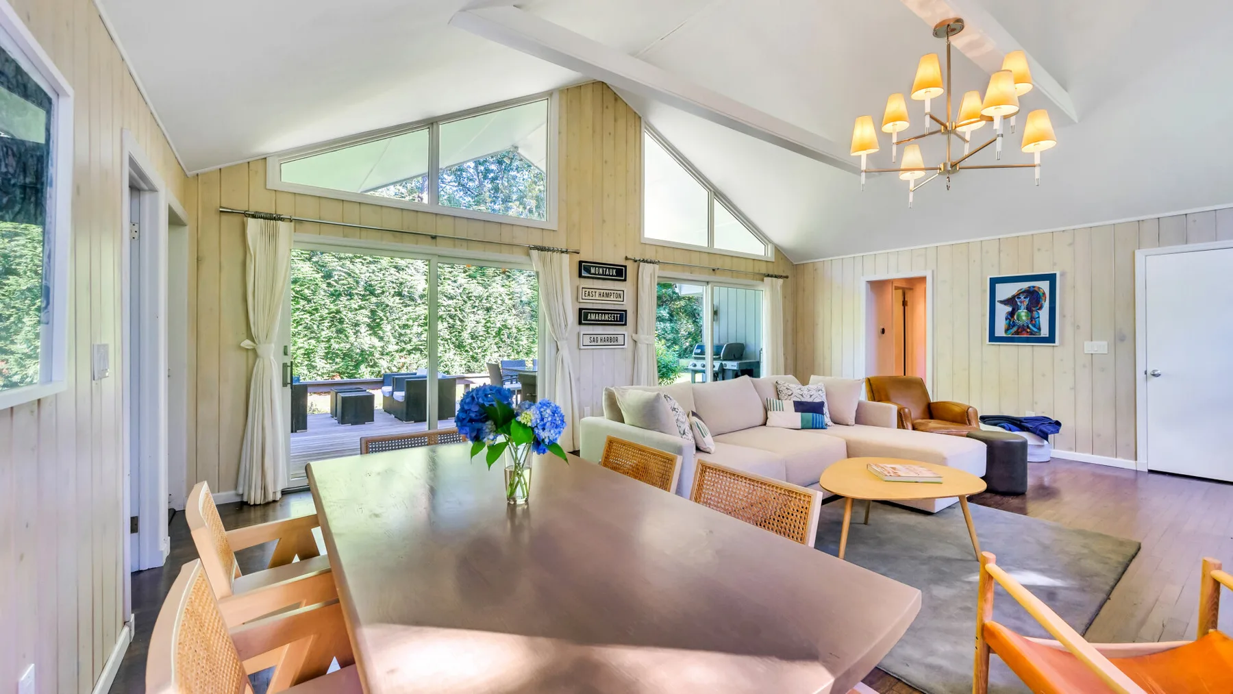 A bright living and dining area with large windows and a long dining table.