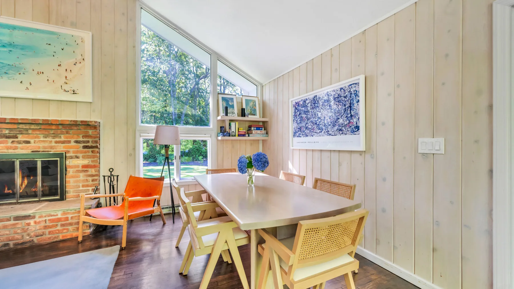 A bright dining area with a long table beside large windows.