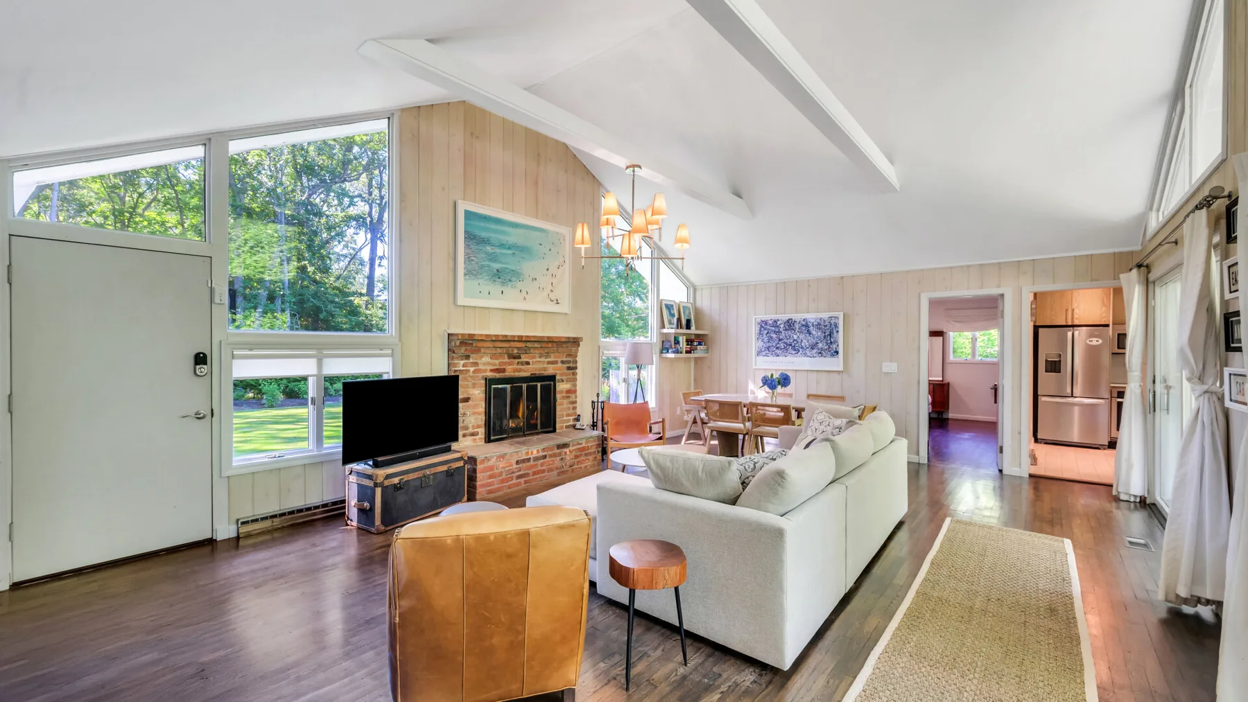 A bright living room with seating arranged around a brick fireplace.