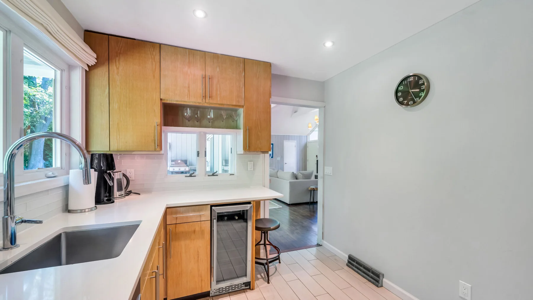A bright kitchen with wooden cabinetry, a sink, and a stainless steel refrigerator.