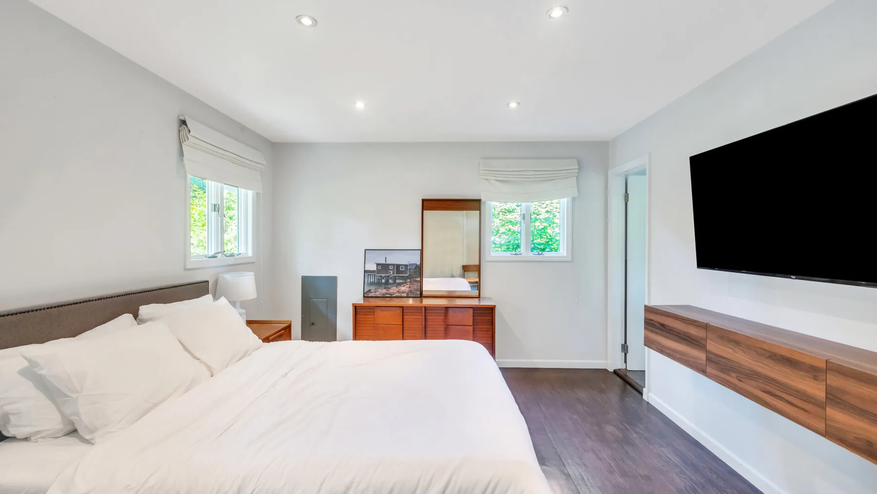 A bright bedroom with a bed and a wall-mounted television.