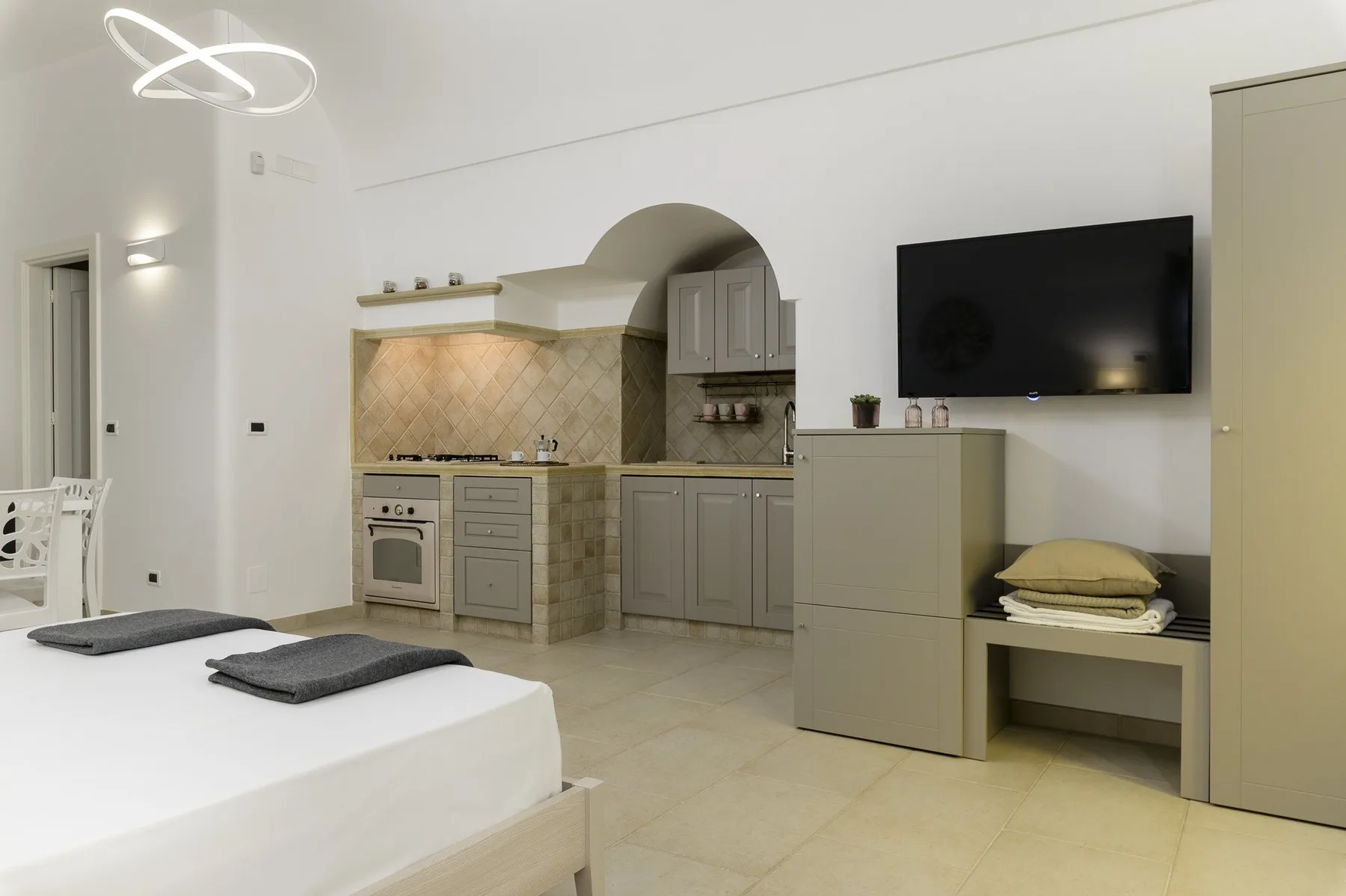 A bright bedroom with a bed and a compact kitchen area.